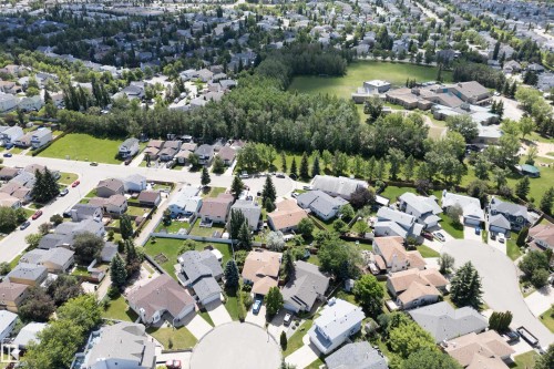 Aerial perspective of a residential community with diverse single-family homes, mature tree lines, and open green spaces - 5607 188A Street, Edmonton, AB 