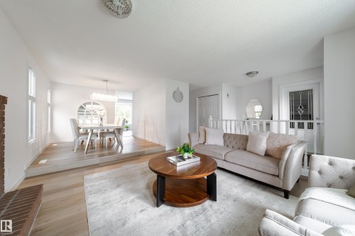 Multi-level main living area featuring light wood-finish flooring, a decorative arched wall niche, and a prominent front entry door with leaded glass - 5607 188A Street, Edmonton, AB 