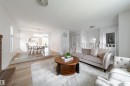 Multi-level main living area featuring light wood-finish flooring, a decorative arched wall niche, and a prominent front entry door with leaded glass - 5607 188A Street, Edmonton, AB 