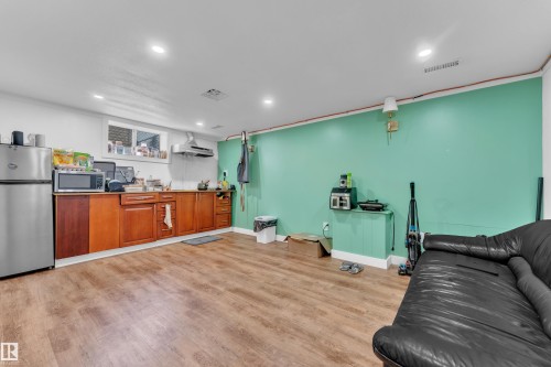 Lower level featuring wood-finish flooring, recessed lighting, and a built-in kitchenette with wood cabinetry and stainless steel appliances - 9606 161 Street, Edmonton, AB 