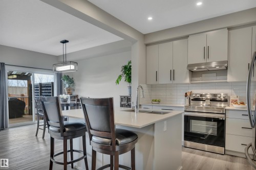 Kitchen featuring light-toned cabinetry, stainless steel appliances, and an island with bar seating - 157 Larch Crescent, Leduc, AB 