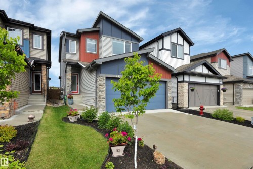 Modern two-story residence featuring a striking red and blue exterior with stone accents - 157 Larch Crescent, Leduc, AB 