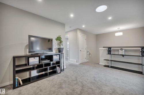 Spacious room with light gray carpeting, recessed ceiling lighting, a circular skylight, and neutral wall tones - 157 Larch Crescent, Leduc, AB 