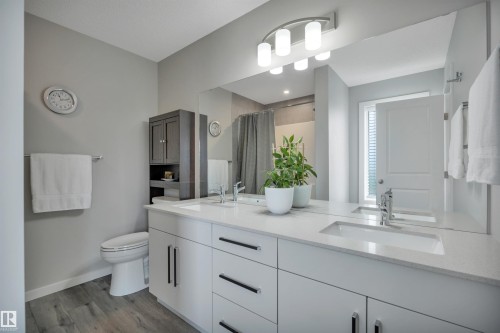 Dual vanity with white cabinetry and integrated sinks set in a light-toned countertop - 157 Larch Crescent, Leduc, AB 