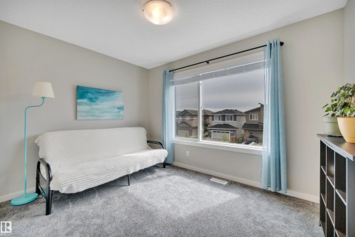 Carpeted room featuring a large window with roller shades and light blue drapes - 157 Larch Crescent, Leduc, AB 