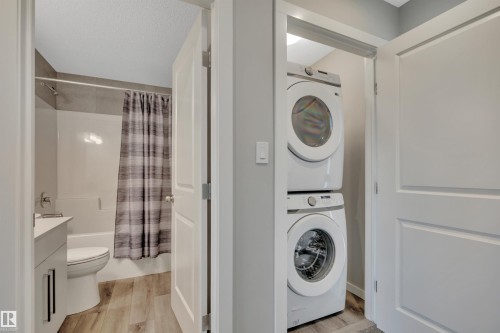 Full-sized stacked laundry appliances in a dedicated alcove - 157 Larch Crescent, Leduc, AB 