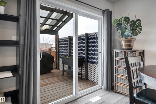 Sliding glass patio door opening to a private outdoor deck with a slatted privacy screen and an overhead trellis - 157 Larch Crescent, Leduc, AB 