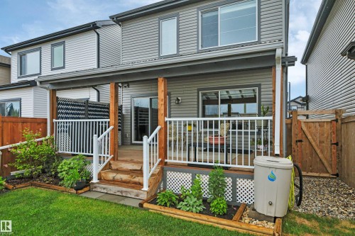 Covered deck featuring wood-finish support posts, white railings, and a privacy screen - 157 Larch Crescent, Leduc, AB 