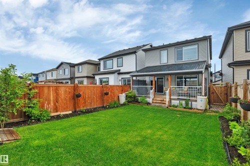 Expansive backyard featuring a manicured lawn, a wood deck with white railings, and a covered patio area - 157 Larch Crescent, Leduc, AB 
