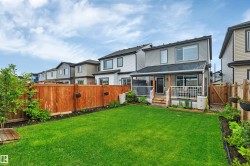 Expansive backyard featuring a manicured lawn, a wood deck with white railings, and a covered patio area - 