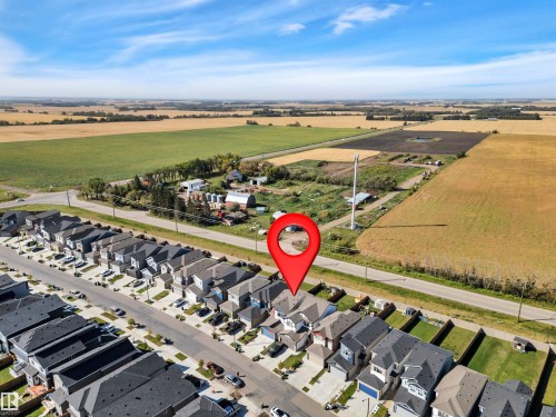 Aerial perspective showcasing a residential street with uniform homes, each featuring a private driveway and attached garage - 157 Larch Crescent, Leduc, AB 