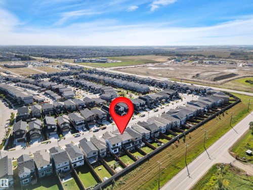 Aerial perspective of a developed residential community featuring rows of modern homes with dark roofs - 157 Larch Crescent, Leduc, AB 