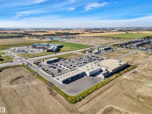 Commercial property featuring a large parking area, multiple building structures, and surrounding undeveloped land - 157 Larch Crescent, Leduc, AB 