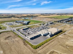 Commercial property featuring a large parking area, multiple building structures, and surrounding undeveloped land - 