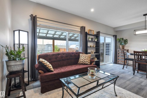 Open-concept living area featuring wood-finish flooring, a contemporary ceiling light fixture, and recessed lighting - 157 Larch Crescent, Leduc, AB 