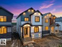 Modern architectural design featuring prominent gables, mixed-material siding including board and batten, stone veneer accents, and dark-framed windows - 18719 130 Street, Edmonton, AB 