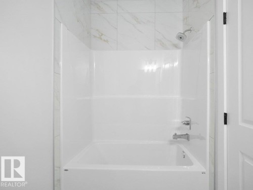 Bathtub and shower combination featuring a white surround and chrome fixtures - 18719 130 Street, Edmonton, AB 