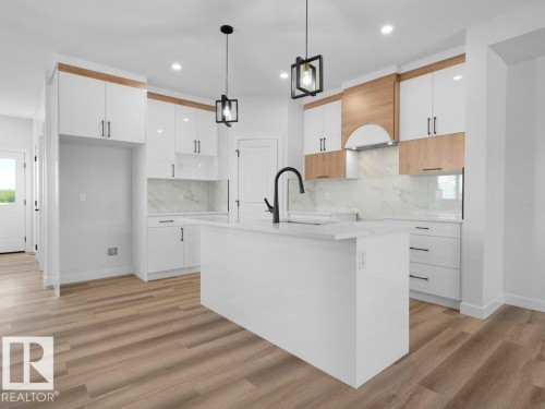 Modern kitchen featuring a central island with an integrated sink and gooseneck faucet - 18723 130 Street, Edmonton, AB 