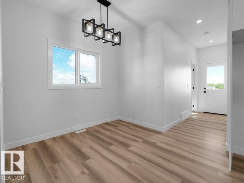 Open-concept space featuring wood-finish flooring and a modern geometric chandelier - 18723 130 Street, Edmonton, AB 