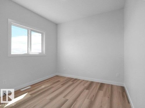 Room featuring a single window with white trim, light gray walls, and wood-finish flooring - 18723 130 Street, Edmonton, AB 