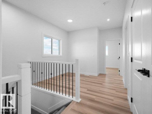 Bright upper-level hallway featuring a white spindle railing with a wood-finish flooring - 18723 130 Street, Edmonton, AB 