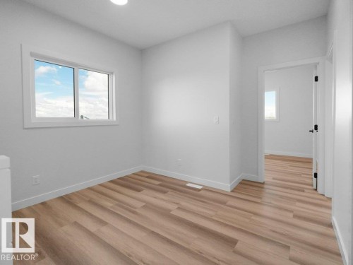 Room featuring wood-finish flooring, white baseboards, and a window with white trim - 18723 130 Street, Edmonton, AB 