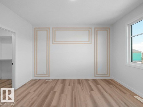 Room featuring decorative wall molding, wood-finish flooring, a white window frame, and a built-in closet with shelving - 18723 130 Street, Edmonton, AB 