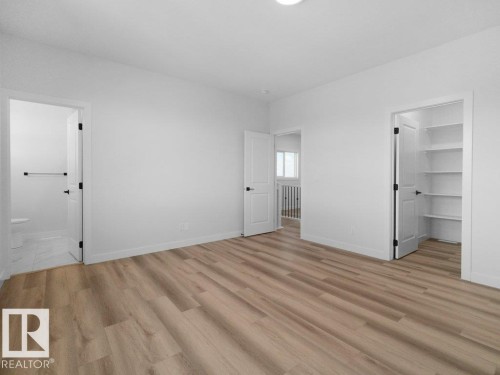 Spacious room featuring light wood-finish flooring, white walls, and a recessed ceiling light - 18723 130 Street, Edmonton, AB 