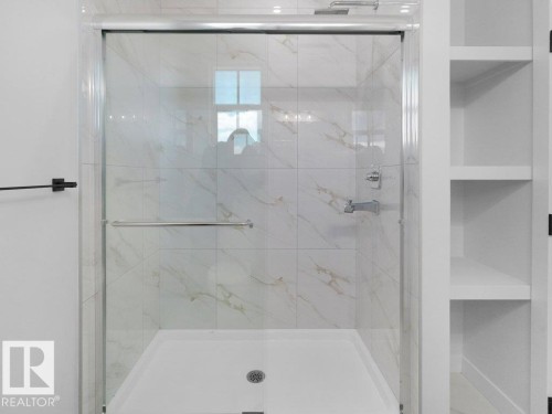 Walk-in shower featuring clear glass enclosure with chrome hardware, white marble-look tile surround, and a white shower pan with central drain - 18723 130 Street, Edmonton, AB 