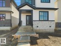 Contemporary exterior featuring vertical and horizontal white siding, light-toned stone veneer accents, and dark trim - 18723 130 Street, Edmonton, AB 