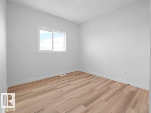 Bright interior space featuring light-colored walls, wood-finish flooring, and a white-framed window - 18723 130 Street, Edmonton, AB 