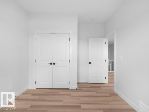 Interior hallway featuring light wood-finish flooring, white walls, and white trim - 18723 130 Street, Edmonton, AB 