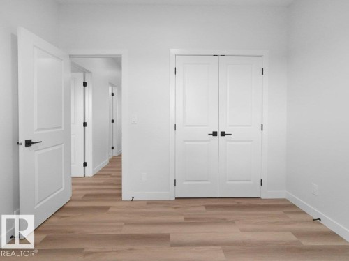 Light wood-finish flooring complements crisp white walls and trim - 18723 130 Street, Edmonton, AB 