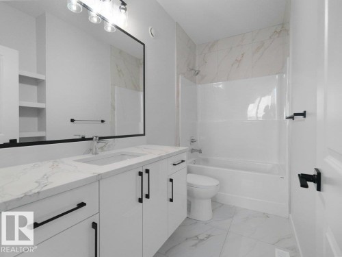 Contemporary bathroom featuring a white vanity with black hardware, an undermount sink, and a stone-finish countertop - 18723 130 Street, Edmonton, AB 