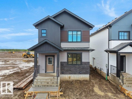 Contemporary two-story residence featuring multi-textured siding, dark-framed windows, a covered front entry, and a concrete stairway with handrails - 18723 130 Street, Edmonton, AB 