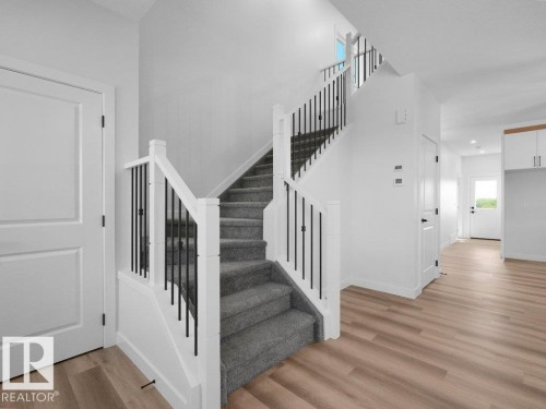 Split-level staircase featuring white newel posts and handrails with black metal balusters - 18723 130 Street, Edmonton, AB 