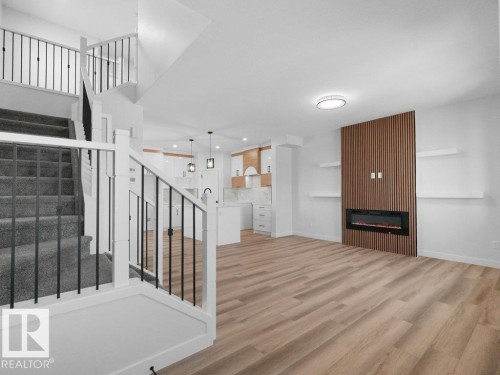 Spacious open-concept living area featuring wood-finish flooring and an electric fireplace with a wood-slat accent wall - 18723 130 Street, Edmonton, AB 
