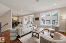 Open-concept living area featuring rich wood-finish flooring, a large multi-pane window, and recessed lighting - 10615 135 Street, Edmonton, AB 