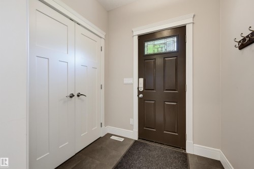 Entryway featuring a dark paneled door with a decorative transom window, white trim, and dark tile flooring - 10615 135 Street, Edmonton, AB 