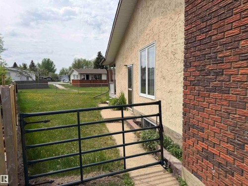 Exterior featuring light stucco siding and a brick accent wall - 5319 63 Street, Redwater, AB 