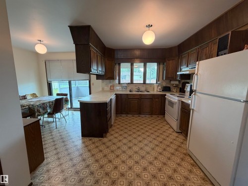Kitchen featuring dark wood cabinetry, light countertops, and patterned floor tiling - 5319 63 Street, Redwater, AB 