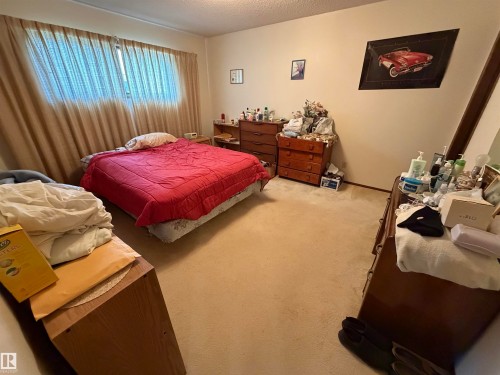 Carpeted room featuring a window with privacy curtains, a ceiling light fixture, and neutral painted walls - 5319 63 Street, Redwater, AB 