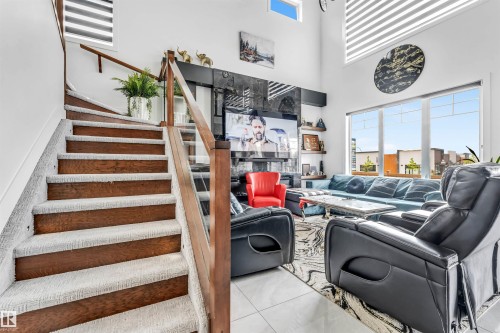 Two-story living area featuring a wood-finish staircase with carpet runners and glass panel railing - 208 33 Street, Edmonton, AB 