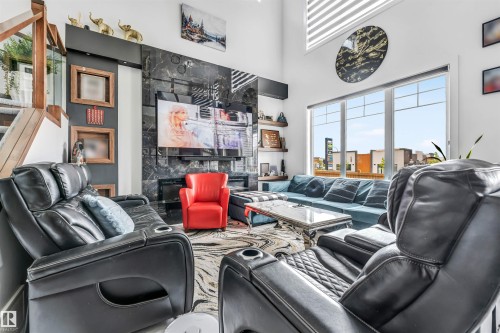 Living area featuring a floor-to-ceiling accent wall with a dark, reflective finish and integrated fireplace - 208 33 Street, Edmonton, AB 