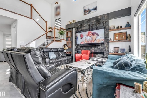 Two-story living area featuring a prominent dark stone-finish fireplace wall with an integrated television display - 208 33 Street, Edmonton, AB 