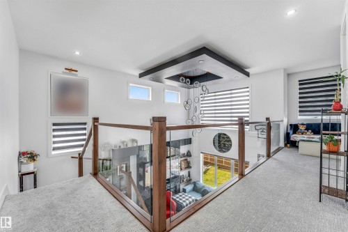 Upper-level hallway featuring light gray carpet, wood-finish and glass railings, and multiple windows - 208 33 Street, Edmonton, AB 