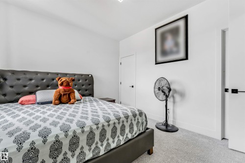 Bedroom featuring light-toned carpeting, white walls, and a white door with a black handle - 208 33 Street, Edmonton, AB 