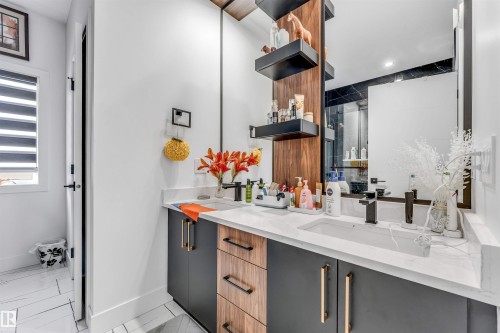 Dual vanity featuring white countertops, modern black faucets, and integrated rectangular sinks - 208 33 Street, Edmonton, AB 