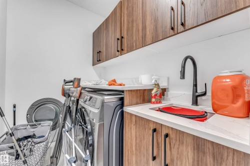 Dedicated laundry space featuring wood-finish cabinetry, white countertops, and a utility sink with a matte black faucet - 208 33 Street, Edmonton, AB 