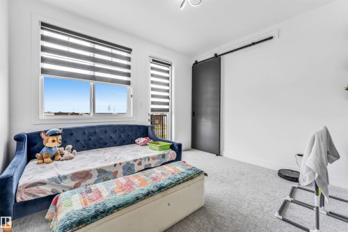Bright interior space featuring a sliding barn door with black hardware, white walls, and light-toned carpeting - 208 33 Street, Edmonton, AB 